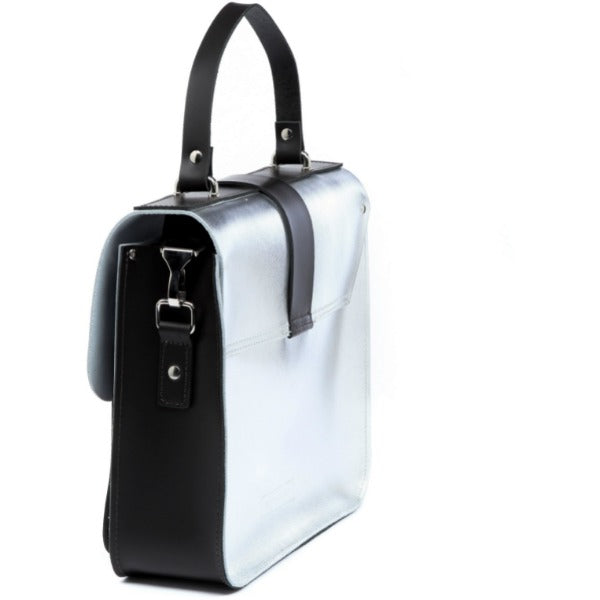 silver leather top handle bag with chocolate calf hair base in a functional side view showing its double front pockets